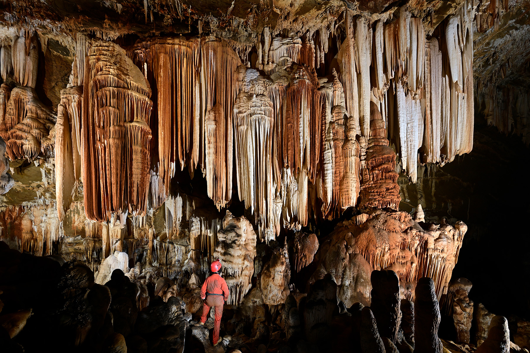 Gruta do Tamboril (Minas Gerais, Brésil) -  Grande paroi décorée de concrétions massives avec personnage de dos en premier plan